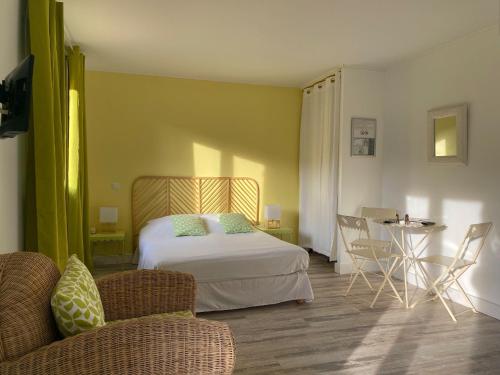 a bedroom with a bed and two chairs and a table at Hôtel Les Calanques in Les Issambres