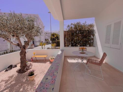 un patio con una mesa y un árbol en el balcón en At the Seacily, en Fontane Bianche