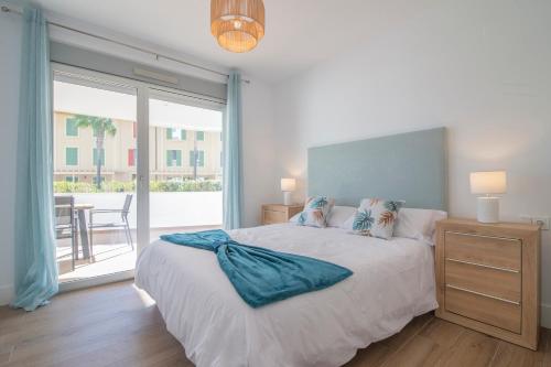 een slaapkamer met een bed en een groot raam bij Halo - Deluxe Apartment With Terrace Steps From The Beach in Sotogrande