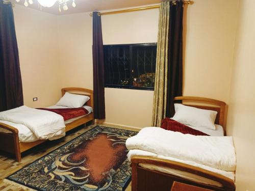 um quarto com duas camas e uma janela em Jordanian Baity Apartment em Wadi Musa