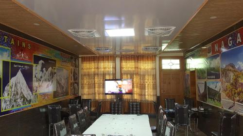 Sala de conferencias con mesas, sillas y TV en Hikal Guest House, en Hunza