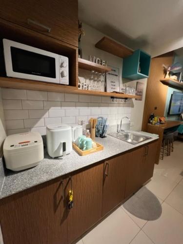 a kitchen with a counter with a sink and a microwave at Suēlo at Cool Suites at Wind Residences Tagaytay in Tagaytay