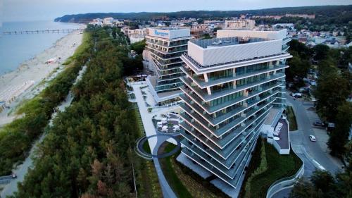 a large white building next to a beach and a building at AXEL WAVE Seaview Apartment &SPA in Międzyzdroje