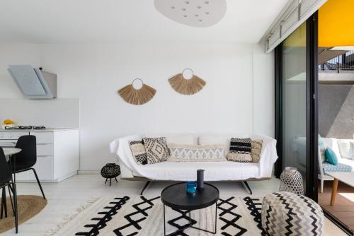 a living room with a white couch and a table at Bright & Chic Condo with Pool & Unique View by FeelHome in Tel Aviv