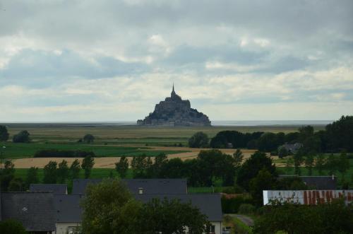 an island in the middle of a field with houses at Aux Chambres du Mont in Huisnes-sur-Mer