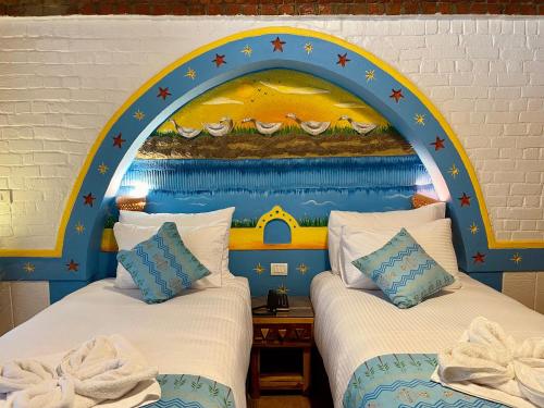 two beds in a room with a painting on the wall at Kato Dool Wellness Resort in Aswan