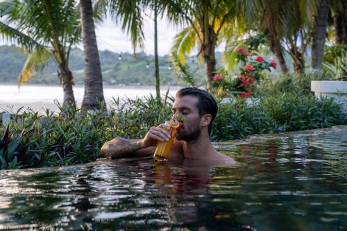 a man drinking a beer in a swimming pool at Villa Marina Lodge & Condos in Playa Venao