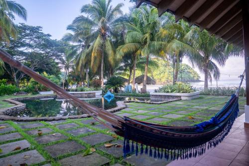 a hammock in a garden with palm trees at Villa Marina Lodge & Condos in Playa Venao