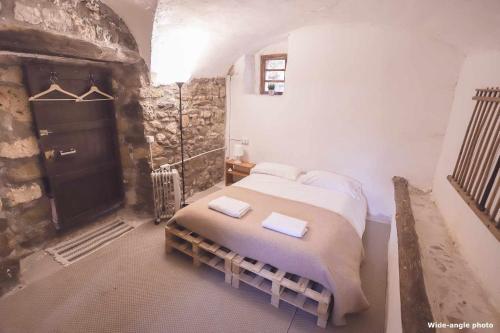 1 dormitorio con 1 cama en una habitación con una pared de piedra en Can Canals y el amor Rectoria de Dosquers en Maia de Montcal