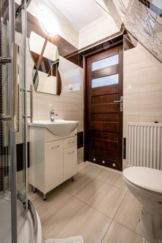 a bathroom with a sink and a toilet and a door at Budzowy Dworek in Murzasichle