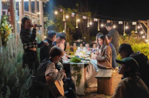 a man taking a picture of a group of people eating at a table at Nguyên căn - Góc sân và Khoảng trời Dalat Homestay in Ấp Phước Thánh