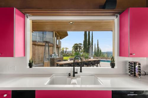 una cocina con armarios rosados, lavabo y ventana en Via Vallarta, en Los Ángeles
