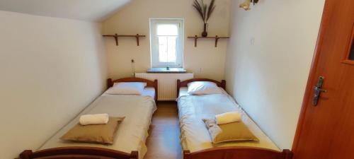 two beds in a small room with a window at Domek w Lesie in Karłów
