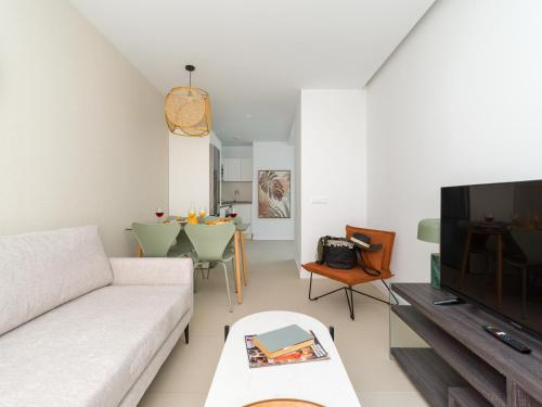 sala de estar con sofá blanco y TV en Royal Suites, en Las Palmas de Gran Canaria
