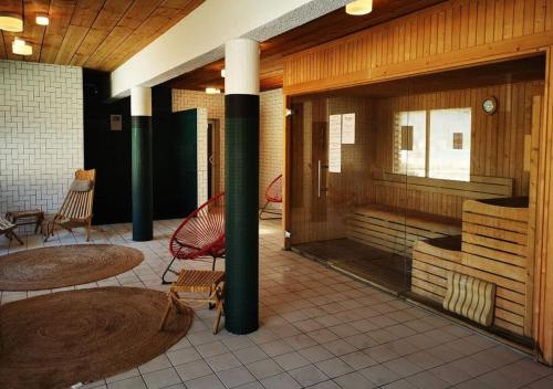 a lobby with a red chair and tables and columns at Mobil home détente Biscarrosse in Biscarrosse