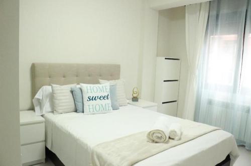 a white bedroom with a large bed with towels on it at Habitación centro Oviedo cerca de estación de buses y trenes in Oviedo