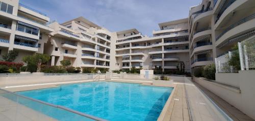 une piscine devant un grand immeuble d'appartements dans l'établissement Le SEXTANT, Frejus Plage, Grand T2, 52 M2 3-4 pers, à Fréjus