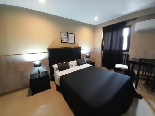 a bedroom with a black bed and a table and chairs at Hotel La Terminal in San Miguel de Tucumán
