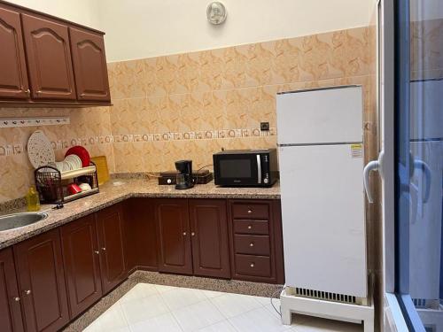 uma cozinha com armários castanhos e um frigorífico branco em Holiday house em Salé