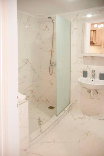 a white bathroom with a shower and a sink at Mariangelas House in Kos