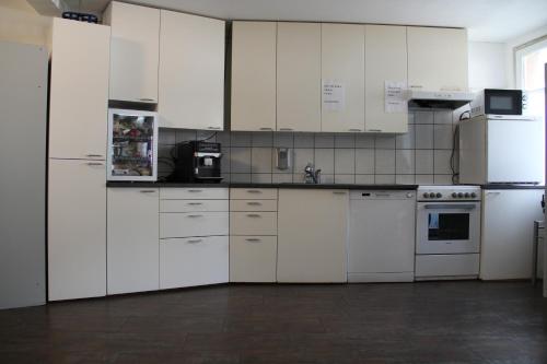 a white kitchen with white cabinets and appliances at Stay2Night City Center Hostel in Zürich