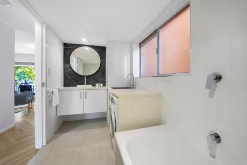 een witte badkamer met een wastafel en een spiegel bij Newly Renovated Unit in Southport Gold Coast in Gold Coast