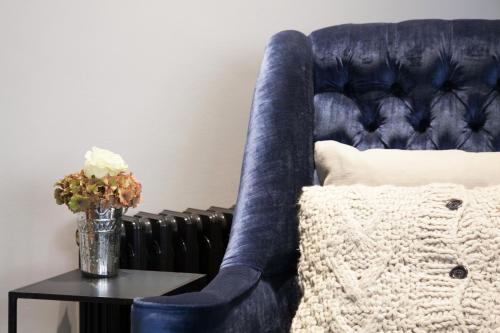 ein blauer Stuhl neben einem Tisch mit einem Kissen in der Unterkunft The Chesterfield Suite in London