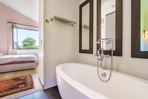 a white bathroom with a tub and a bed at Dépendance paisible proche Océan in Arbonne