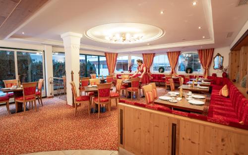 um restaurante com cadeiras vermelhas, mesas e janelas em Sylvana's Wohlfühl Hotel em Mayrhofen