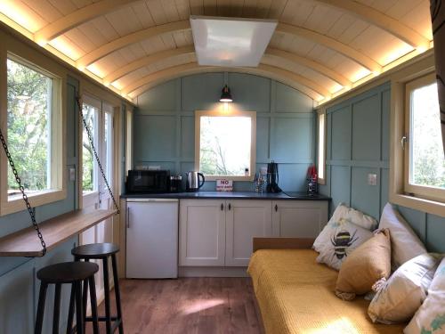 una pequeña cocina con sofá en una casa pequeña en The Woodpecker shepherd hut, en Elmswell