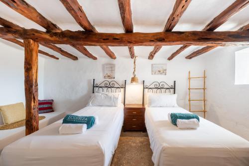 Villa Torre Bes في سان أنطونيو: سريرين في غرفة مع عوارض خشبية