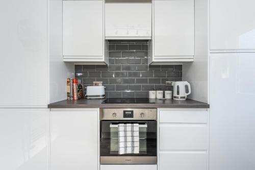 a kitchen with white cabinets and a stove at 14 Acomb Wood Drive Peaceful 2-Bed Home in York with Free Parking - Pass the Keys in York