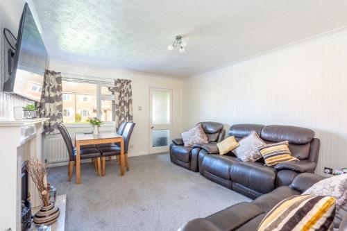 a living room with a leather couch and a table at 14 Acomb Wood Drive Peaceful 2-Bed Home in York with Free Parking - Pass the Keys in York