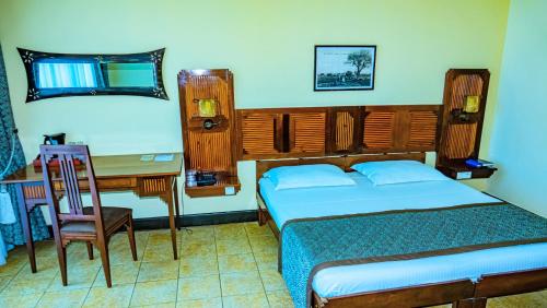 a bedroom with a bed and a desk and a bed and a chair at Le Grand Hôtel Diego in Diego Suarez