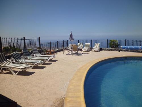 una fila de sillas y una piscina con el océano en Villa El Mirador, en Los Menores
