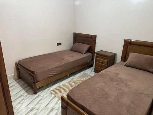 een slaapkamer met 2 bedden en 2 nachtkastjes bij appartement meublé à Laâyoune in Laayoune