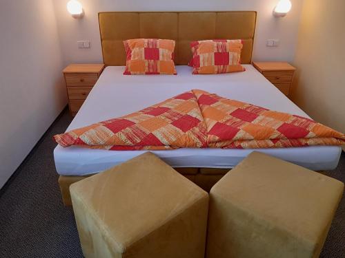 a bedroom with a bed with two ottomans at Pension Jana - Wellness in Jilemnice