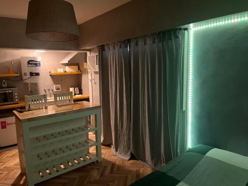 Schlafzimmer mit grünen Vorhängen und einem Bett mit Tisch in der Unterkunft Monoambiente Moderno 2 cuadras Plaza de Mayo in Buenos Aires