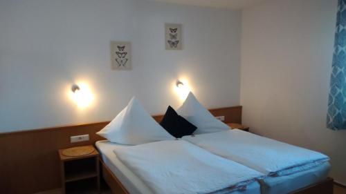1 dormitorio con 1 cama con sábanas y almohadas blancas en Kräuterhex' Reutin en Alpirsbach
