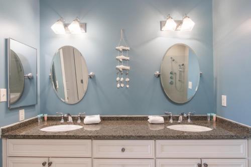 a bathroom with two sinks and two mirrors at Levins Bend at The Wharf in Orange Beach