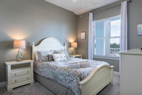 a bedroom with a bed with two night stands and a window at Levins Bend at The Wharf in Orange Beach