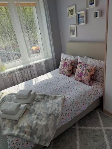 a bedroom with a bed with pillows and a window at Bee Happy Apartament Wrzesnia in Września