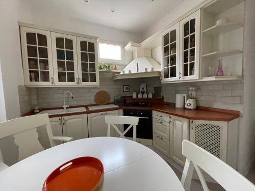 a kitchen with white cabinets and a white table and chairs at Linden Korzo with balcony in Rijeka
