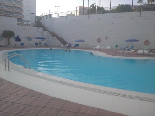 een groot zwembad met blauw water in een gebouw bij Relax Playa Ingles in Playa del Inglés