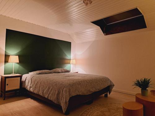 a bedroom with a large bed with a green headboard at Le Chalet - Maison de vacances in La Roche-en-Ardenne