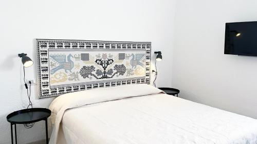 Schlafzimmer mit einem weißen Bett mit gemustertem Kopfteil in der Unterkunft Casa Stewart - Levante in Geremèas