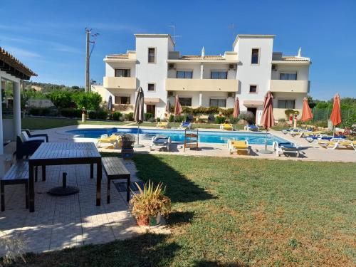 a large apartment building with a pool and a table at Residence 1000 Roses in Moncarapacho