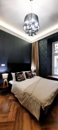 a bedroom with a large bed and a chandelier at Apartament Milonga in Krakow