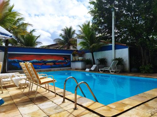 a swimming pool with two chairs and a couch at Pousada Chez Soleil CibrateI Itanhaém in Itanhaém