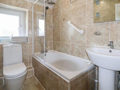 uma casa de banho com uma banheira, um WC e um lavatório. em Ty Pen Y Bryn em Conwy